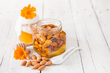almonds with honey in a jar on a table, selective focus