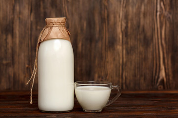 Bottle of milk and cup on rustic wooden table