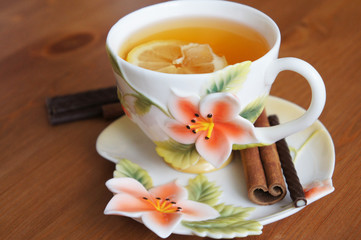 Cup of tea decorated by red flower with lemon and cinnamon