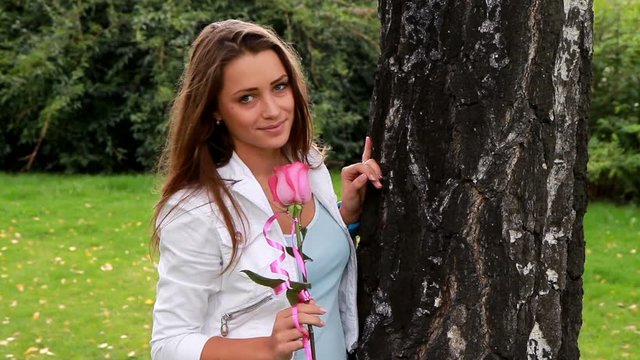 Beautiful girl posing with rose in the park.