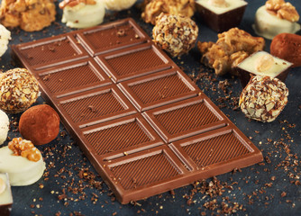 Bar of milk chocolate close up and variety of candy