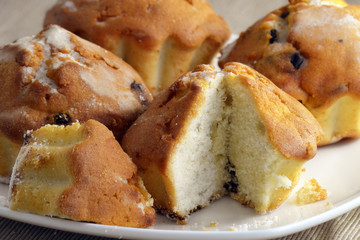 Fresh buns with raisins on a white plate close-up.