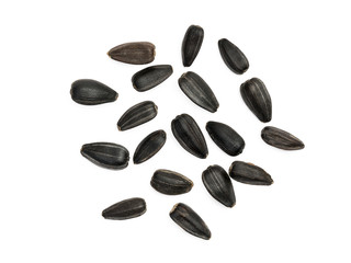 Some black sunflower seeds spread out on white background seen from above