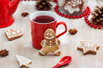 Tea, ginger man cookie and and red spoon on plywood background