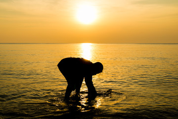 silhouette of Fisherman working in sunrise at thailand beach 