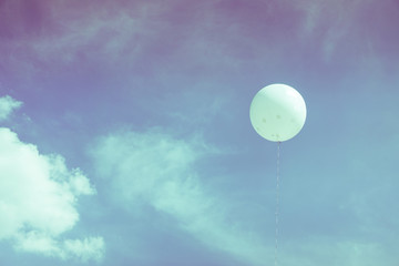 White balloons floating in the sky with clouds.