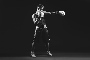 Fototapeta na wymiar Young boxer sportsman on black background