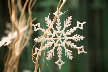 Светло-бежевая снежинка на оголенных бежевых веточках веточках на оливковом фоне