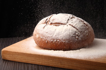 bread/ bread, flour sprinkled on an oak board on a dark background