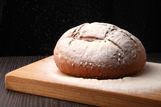 bread/ bread, flour sprinkled on an oak board on a dark background
