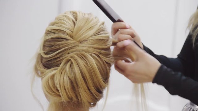 Hairdresser make French twist evening wedding hairstyle in beauty hair salon.