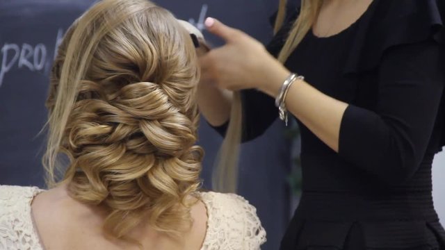 Hairdresser coiffeur makes lush french twist hairstyle.