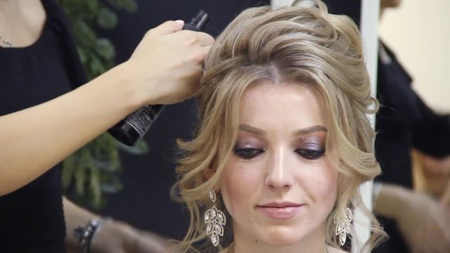 Professional hairdresser makes hairstyle for a long hair model