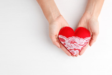 Female hands holding red heart on light background