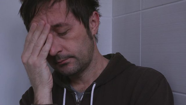 Depressed unhappy man crying lonely in bathroom