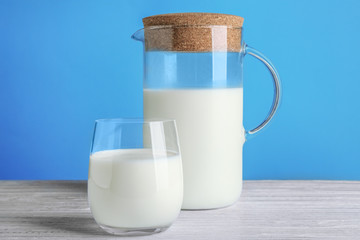 Milk in glass and jug on white wooden table, closeup