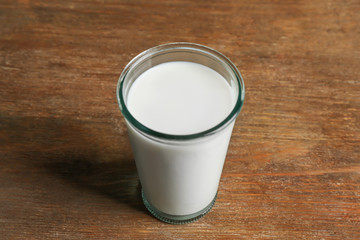 Glass of milk on blurred wooden background, closeup