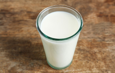 Glass of milk on blurred wooden background, closeup