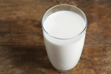 Glass of milk on blurred wooden background, closeup