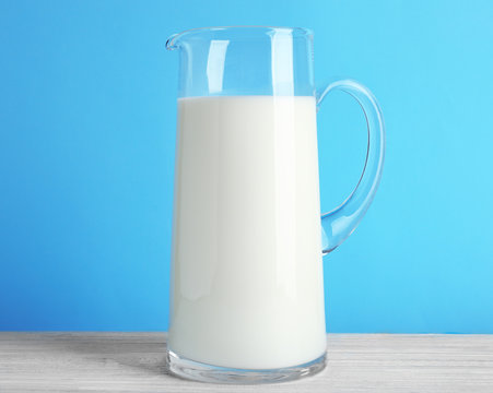 Jug of milk on white wooden table, closeup