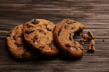 Tasty cookies with chocolate chips and crumbs on wooden background
