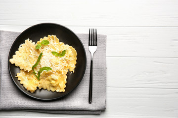 Plate of ravioli with cheese on table