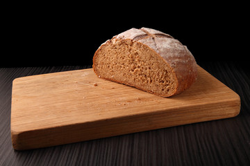 bread, cut on an oak board/ bread, cut on an oak board on a dark background