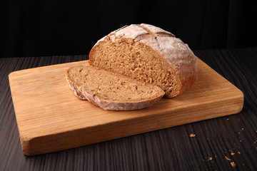bread, cut on an oak board/ bread, cut on an oak board on a dark background