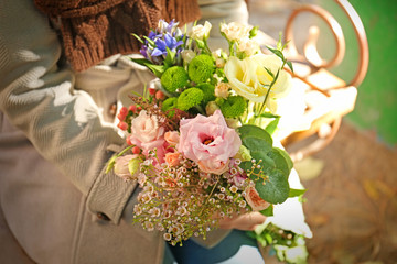 Closeup of female hands holding stylish bouquet of beautiful flowers