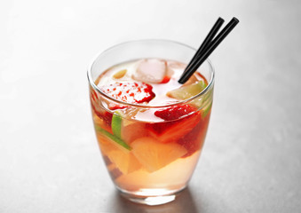 Glass of cold fruit cocktail on light background
