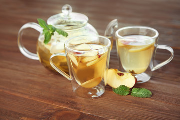 Tasty tea with apple, lemon and mint on wooden background