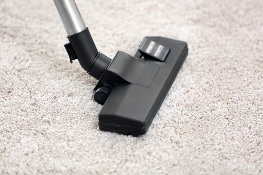 Cleaning carpet in room with hoover
