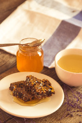 Honeycombs and honey in jar and green tea on wooden background