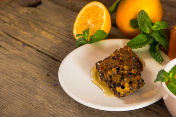 Honeycomb, honey in jar, green tea, lemon with leaf and mint on