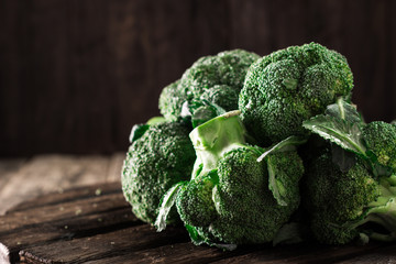 Fresh green broccoli in wood bowl over rustic wooden background