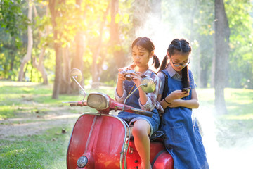 Asian children are sitting on the motorcycle.