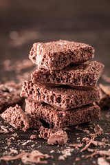 Porous chocolate in stack on a wooden background closeup.