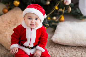 funny baby boy weared in Santa hat with golden Christmas ball