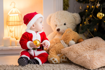 funny baby boy weared in Santa hat with golden Christmas ball