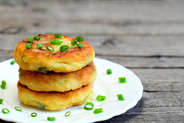 Fried vegetable patties on a plate. Delicious patties made of potatoes, green peas, carrot and green beans and garnished with fresh green onion. Vegetarian lunch or dinner idea. Vintage style. Closeup