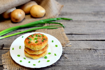 Roasted vegetable patties on a plate. Healthy patties cooked of potatoes, green peas, carrots and green beans. Vegetarian lunch or dinner idea. Fresh vegetables on wooden background with copy space