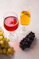 Wine and grapes. White and red wine in glasses on light marble b