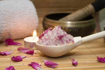 Obraz na płótnie Canvas homemade body scrub from sea salt and rose petals and peony, Tibetan bowl,candle,pink towel on a straw Mat. Spa concept