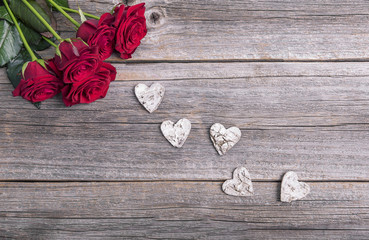 Red roses and heart on a wooden background.