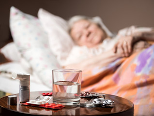 Sick old woman lying in bed at home