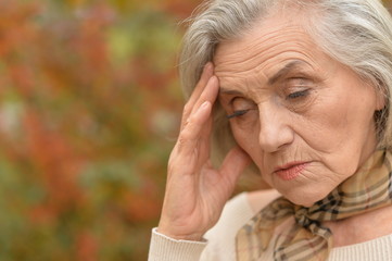 Sad elderly woman in autumn park