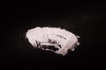 white narcotic drug dust on black background