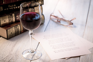 Books, a glass of wine and poetry on the old wooden table. Shakespeare Poems