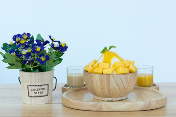 Bingsu ( Korea food) mango served with sweetened condensed milk and flowers vase on table