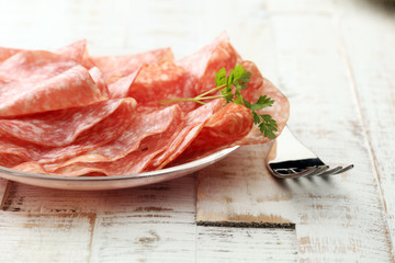 thinly sliced salami on a wooden texture on the background